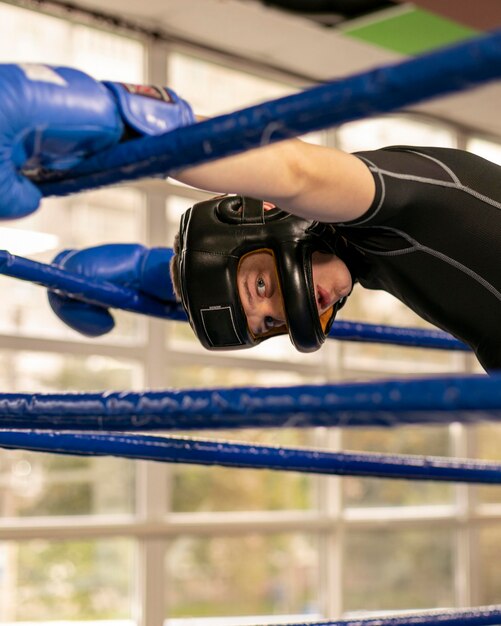 Mannelijke bokser met handschoenen en helm in de ring