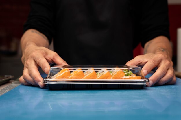 Mannelijke chef-kok bereidt een sushi-bestelling voor een afhaalmaaltijd