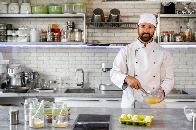 Mannelijke chef-kok in de keuken die eieren gebruikt om te koken