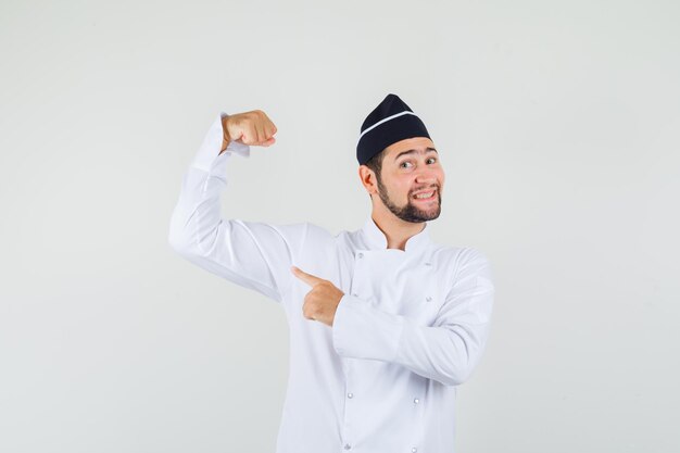 Mannelijke chef-kok in wit uniform toont zijn armspieren en ziet er zelfverzekerd uit, vooraanzicht.