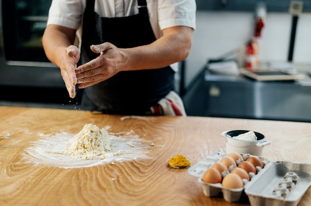 Mannelijke chef-kok met schort die deeg voorbereiden