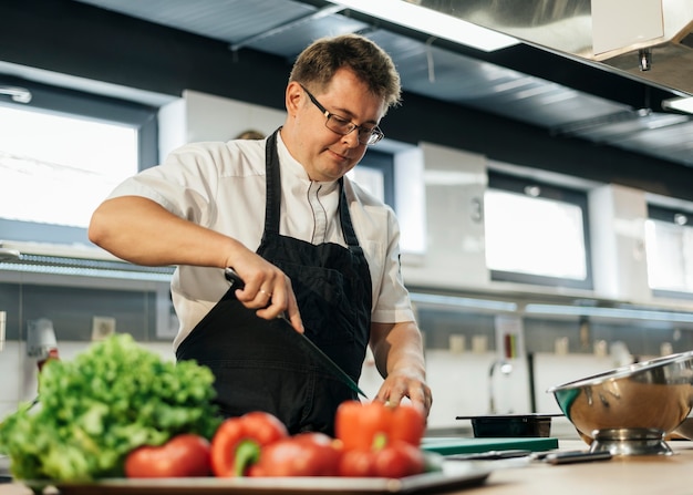 Mannelijke chef-kok tomaten hakken in de keuken