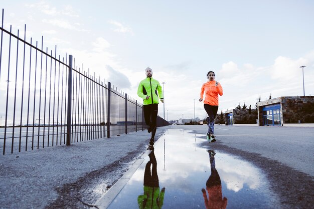 Mannelijke en vrouwelijke atleet die op straat loopt