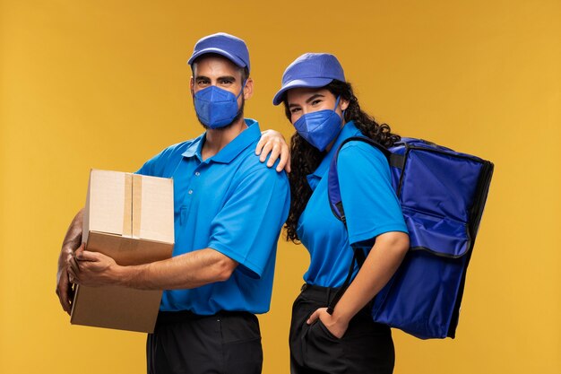 Mannelijke en vrouwelijke bezorgers met medische maskers met kartonnen doos en rugzak