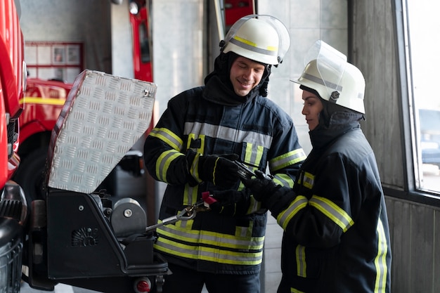 Mannelijke en vrouwelijke brandweerlieden werken samen in pakken en helmen