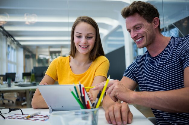 Mannelijke en vrouwelijke grafisch ontwerpers bespreken via digitale tablet