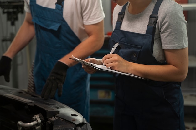 Mannelijke en vrouwelijke monteurs werken in de winkel aan een auto