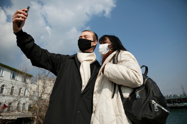 Mannelijke en vrouwelijke toeristen die buiten een selfie maken met hun smartphone