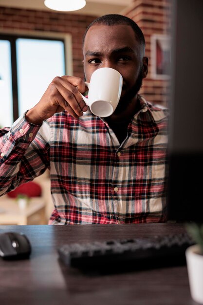 Mannelijke freelancer die een computerwebsite gebruikt om online zaken op afstand te doen, onderzoeksgegevens te vinden om een rapport te maken. Op afstand werken vanuit huis en e-mailen, webinar les volgen.