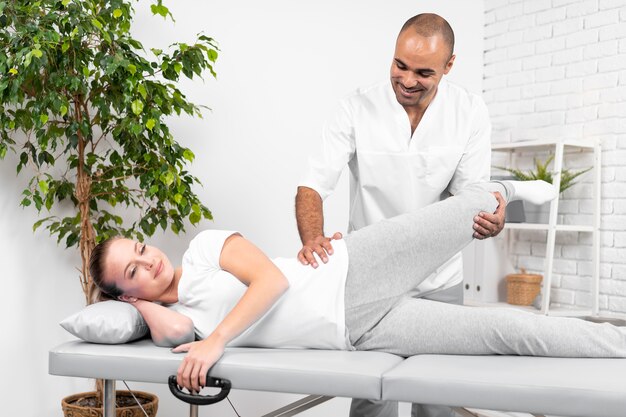 Mannelijke fysiotherapeut die de heupmobiliteit van de vrouw controleert