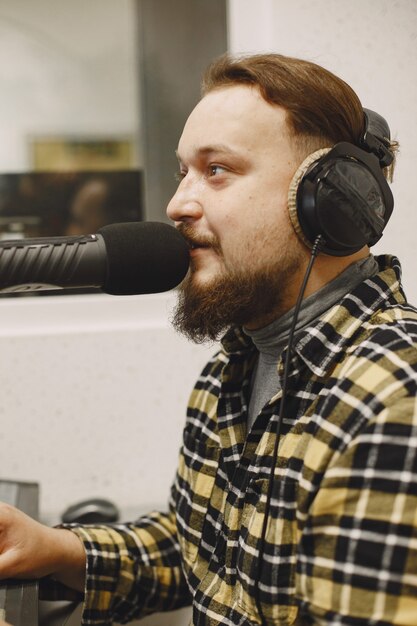 Mannelijke gastheer die op microfoon communiceert. Man in radiostudio.