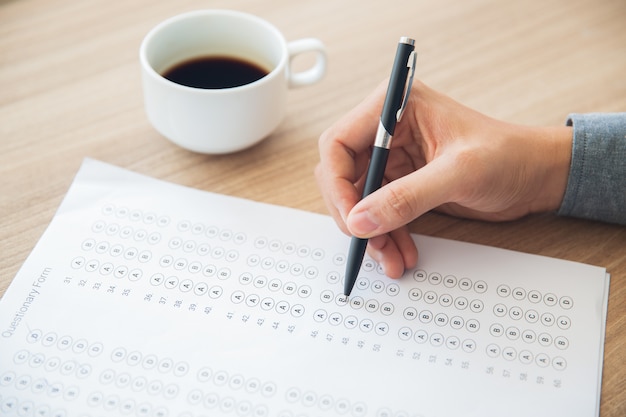 Gratis foto mannelijke hand te beantwoorden vragenlijst vorm met pen