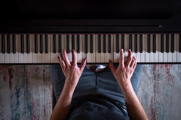 Mannelijke handen op het bovenaanzicht van de pianotoetsen