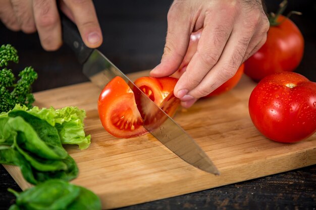 Mannelijke handen snijden groenten voor salade