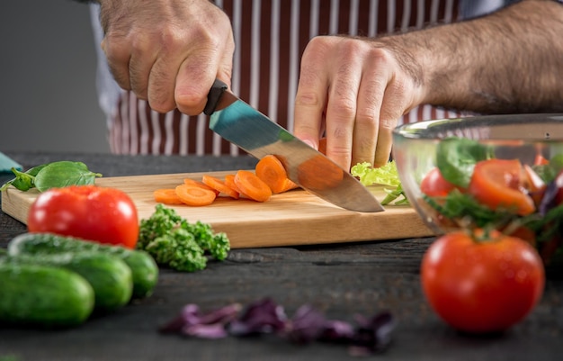 Mannelijke handen snijden groenten voor salade