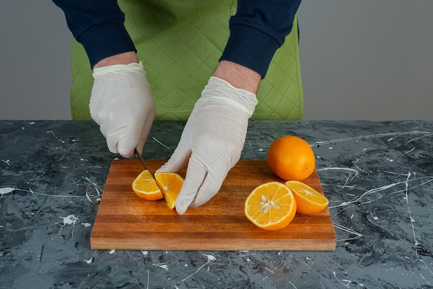 Mannelijke handen snijden verse citroen op marmeren tafel.