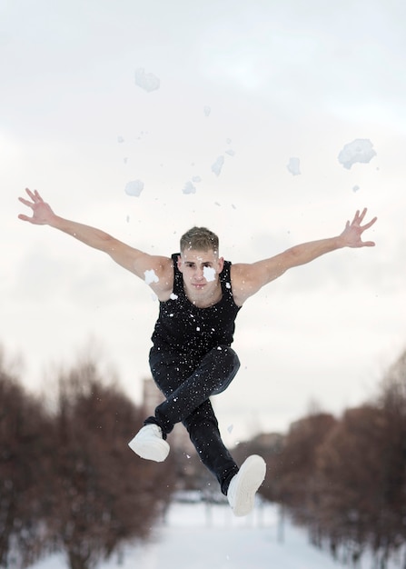 Mannelijke hiphopkunstenaar die met buiten sneeuw dansen