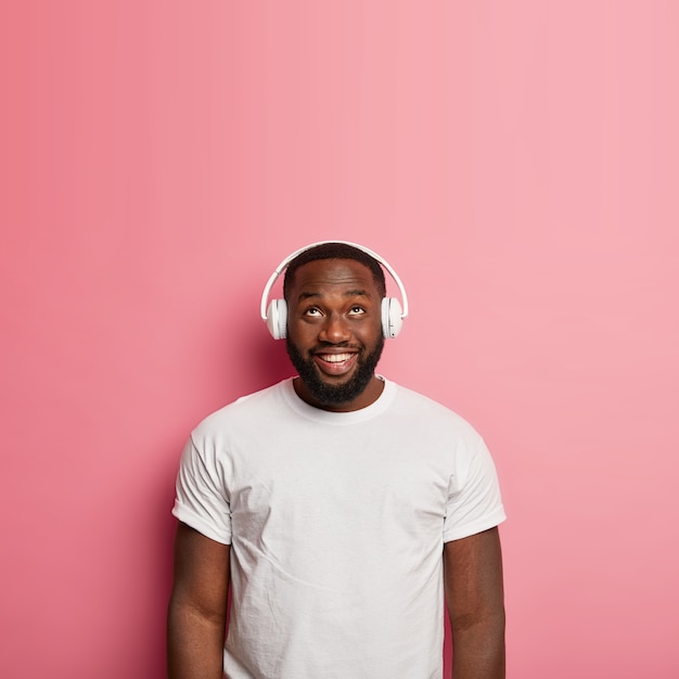 Mannelijke hipster luistert naar muziek in draadloze hoofdtelefoons geïsoleerd