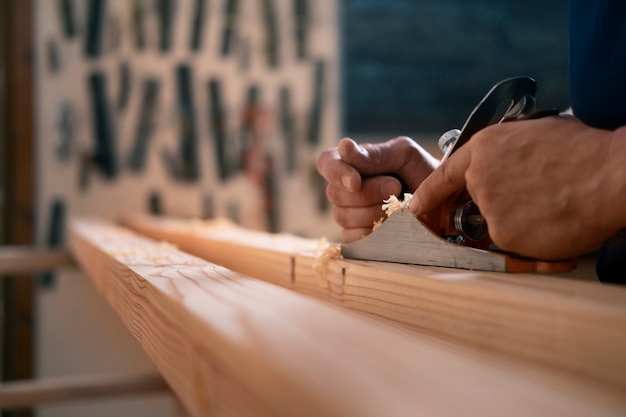 Gratis foto mannelijke houtbewerker in zijn winkel die werkt met gereedschappen en apparatuur