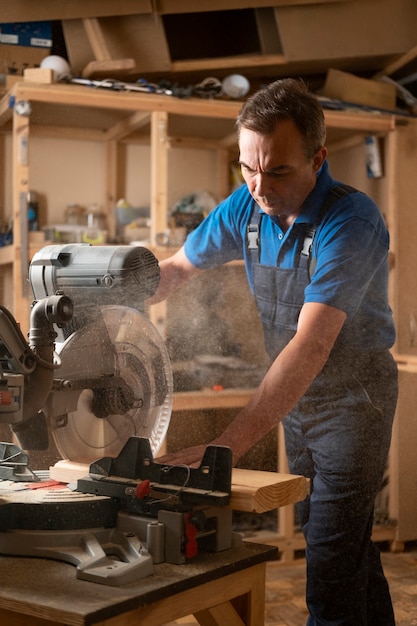 Gratis foto mannelijke houtbewerker in zijn winkel die werkt met gereedschappen en apparatuur