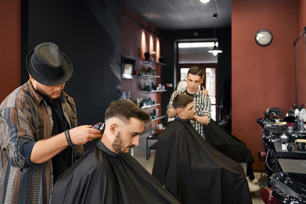 Mannelijke klanten zitten in rijen in de salon terwijl ze worden geknipt