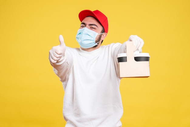 mannelijke koerier in masker met bezorgkoffie op geel