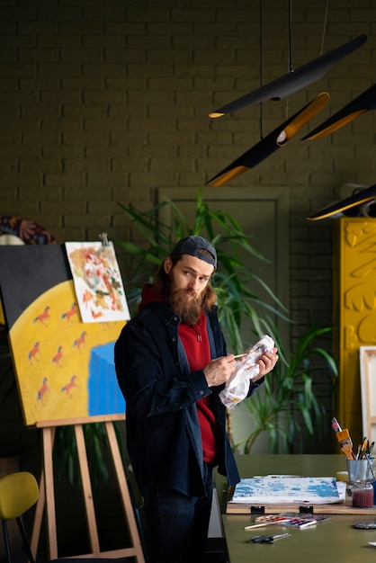 Gratis foto mannelijke kunstenaar schilderen met waterverf in de studio