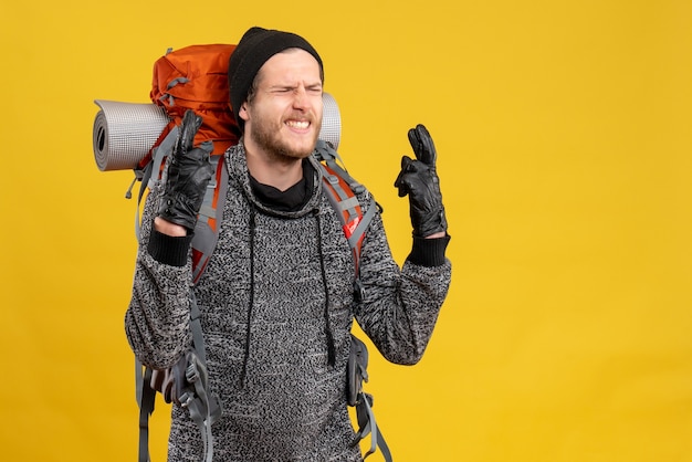 mannelijke lifter met leren handschoenen en rugzak die een wensteken maakt