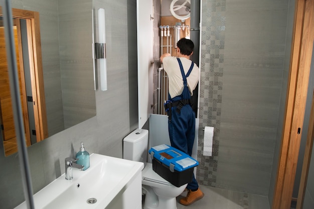 Gratis foto mannelijke loodgieter die problemen oplost in het huis van een klant