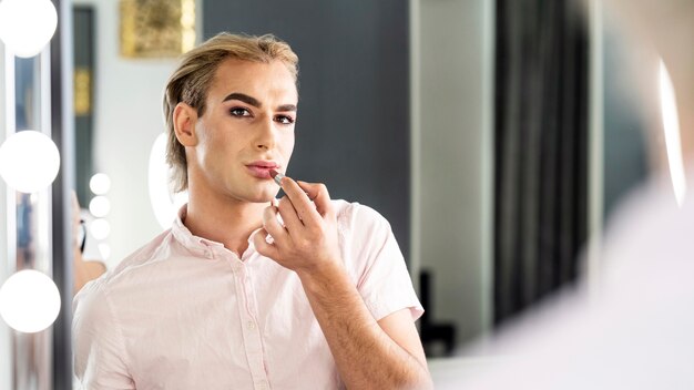 Mannelijke make-up kijkt in de spiegel