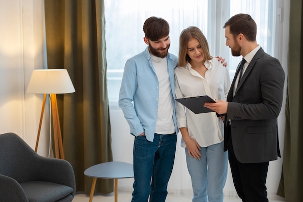 Gratis foto mannelijke makelaar in onroerend goed die zaken doet en huis laat zien aan een potentieel kopend stel