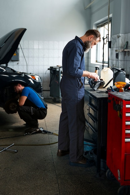 Gratis foto mannelijke monteurs werken samen aan auto in de winkel