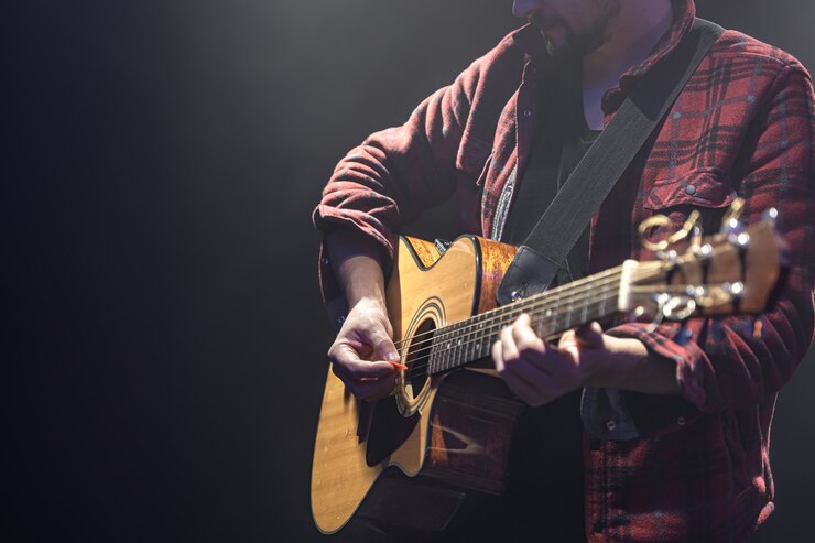 Gratis Foto mannelijke muzikant akoestische gitaar spelen in een donkere kamer kopiëren ruimte.