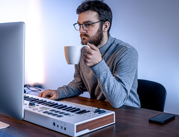 Mannelijke muzikant maakt muziek met behulp van de werkplek van computer- en toetsenbordmuzikanten