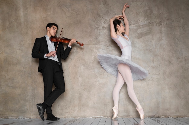 Gratis foto mannelijke muzikant viool spelen terwijl ballerina danst