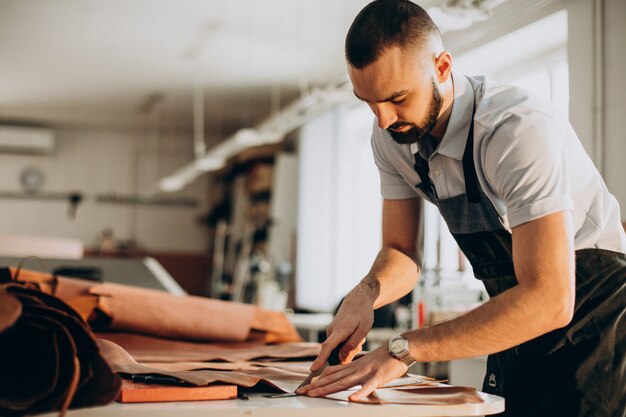 Mannelijke ontwerper en leerkleermaker die in een fabriek werken