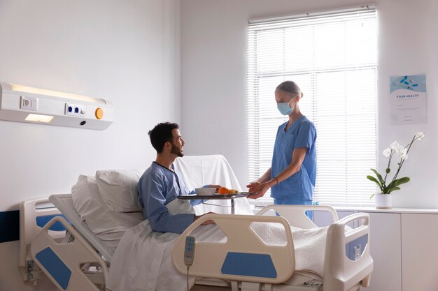 Mannelijke patiënt in bed praten met een verpleegster
