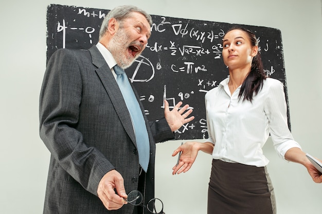 Mannelijke professor en jonge vrouw tegen schoolbord in de klas