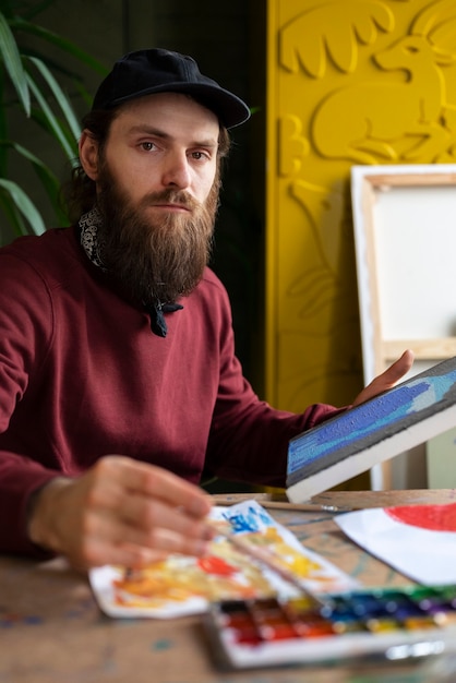 Gratis foto mannelijke schilder die aquarel gebruikt op zijn kunst in de studio