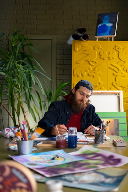 Mannelijke schilder in de studio die aquarel gebruikt voor zijn kunst