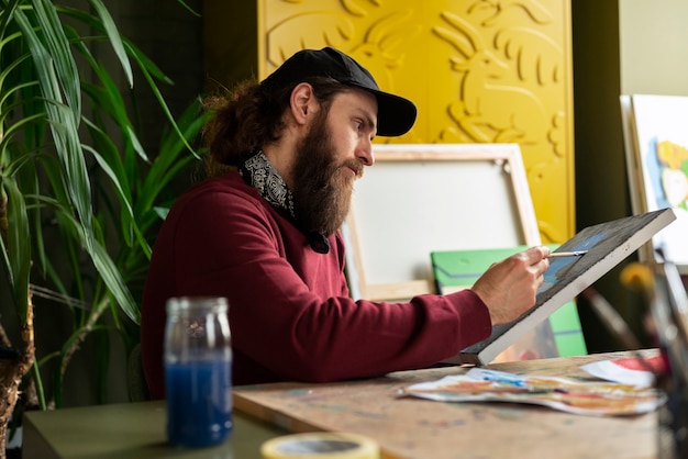 Gratis foto mannelijke schilder in de studio met waterverf op zijn kunst