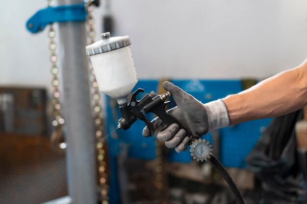 Mannelijke schilder in overall die zijn werk doet in de autowinkel