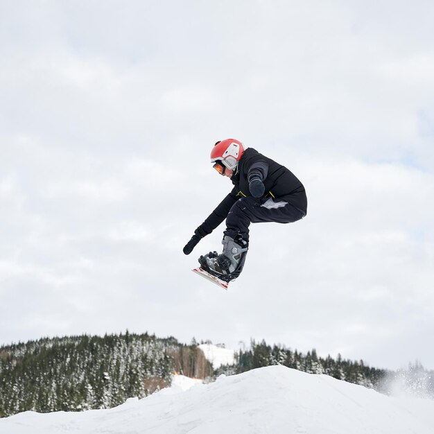 Mannelijke snowboarder die trucs in de lucht doet bij skitoevlucht