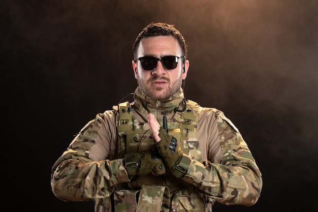 Mannelijke soldaat in camouflage op de donkere muur