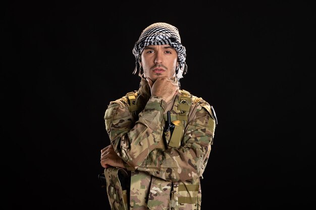 Mannelijke soldaat in camouflage op de zwarte muur