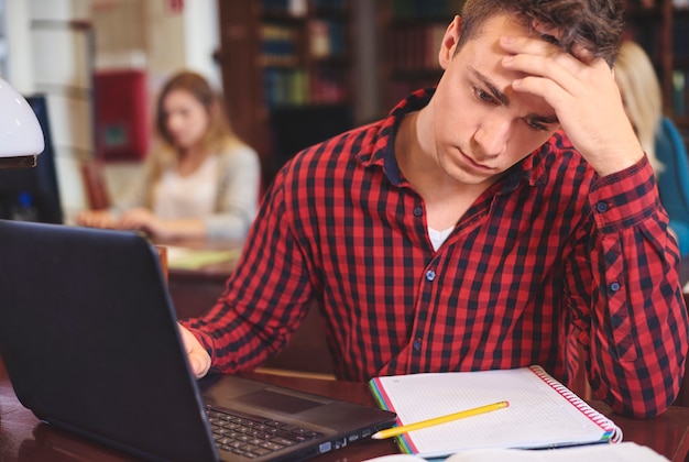 Mannelijke student die aan de computer studeert