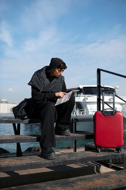 Mannelijke toerist die kaart naast koffer controleert