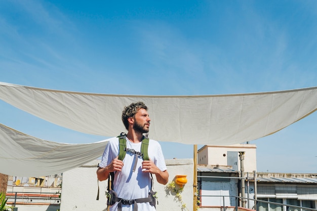 Mannelijke toerist met rugzak die zich onder zonnescherm bevindt