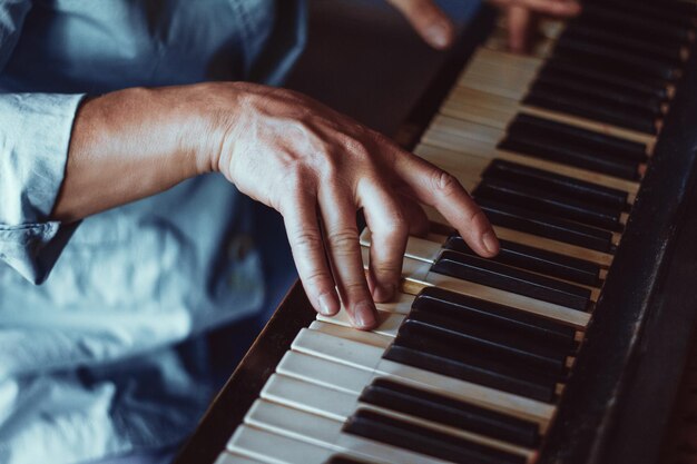 Mannelijke vingers die de pianotoetsen aanraken