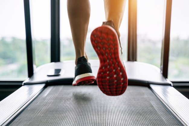 Mannelijke voeten in sneakers uitgevoerd op de loopband in de sportschool. Oefening concept.